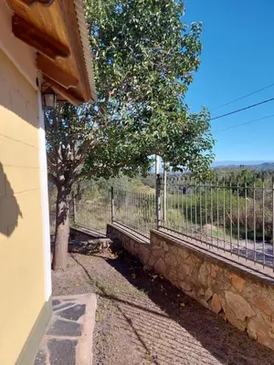 a fence and a tree next to a tree at Cabaña Aikén in Embalse