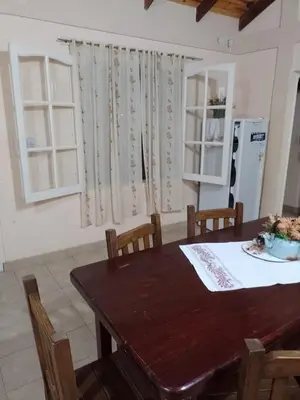 a kitchen with a wooden table with chairs and a refrigerator at Cabaña Aikén in Embalse