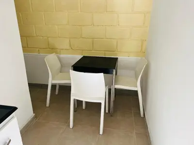 a table and chairs in a room with a wall at Departamentos Arroyo de Los Patos in Arroyo de Los Patos