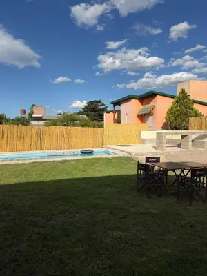 a patio with a table and chairs in a yard at Casa con pileta a 2 cuadras del río in San Antonio de Arredondo
