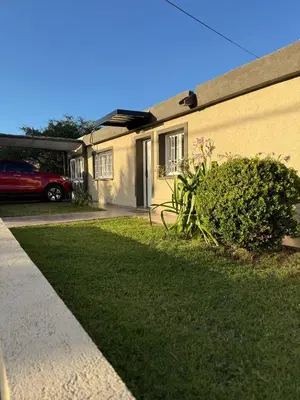 a house with a green yard next to a building at Casa con pileta a 2 cuadras del río in San Antonio de Arredondo