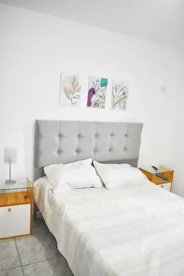 a bedroom with a white bed with two pictures on the wall at Secret Garden in San Antonio de Arredondo