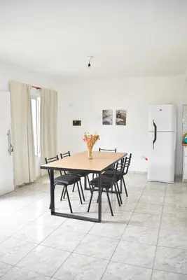 a dining room table with chairs and a refrigerator at Secret Garden in San Antonio de Arredondo