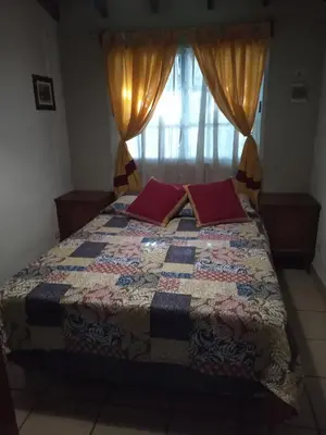 a bedroom with a bed with a quilt and a window at La Rinconada Nono in Nono