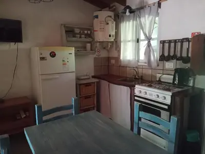 a kitchen with a table and a stove and a refrigerator at La Rinconada Nono in Nono