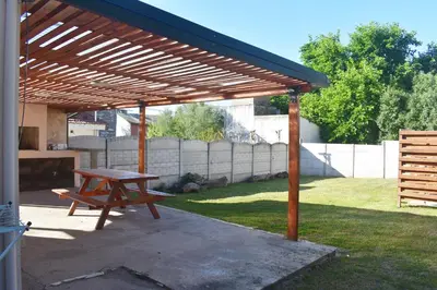 a wooden picnic table under a wooden pergola at Oasis casa de descanso in Villa Carlos Paz
