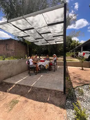 a group of people sitting at a table under a pergola at Apart La Ideal in Villa Cura Brochero