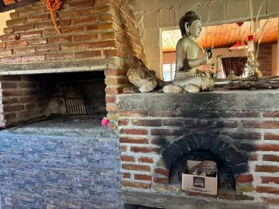 a statue of a buddha sitting on top of a brick fireplace at La luisa segunda in Villa Parque Siquiman