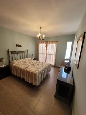 a bedroom with a bed and a table and a window at Depto Palmar in Villa Carlos Paz