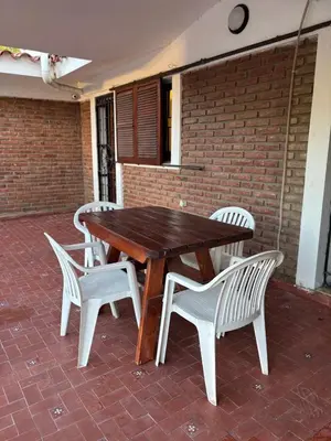 a wooden table and four white chairs sitting around it at Complejo playa de oro 1 in Villa Carlos Paz