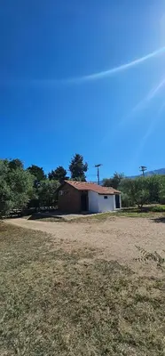 a barn and a field in front of a building at Cabaña el fede in Carpintería