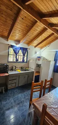 a kitchen with wooden ceilings and a table and chairs at Cabaña el fede in Carpintería