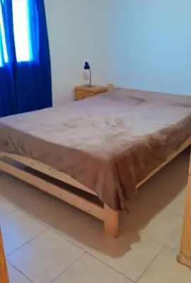 a bed with a wooden frame in a room at Mirador de las Sierras in Villa Parque Siquiman