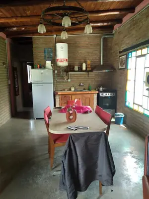 a kitchen with a table with chairs and a refrigerator at Elparadorlasbajadas in Las Bajadas