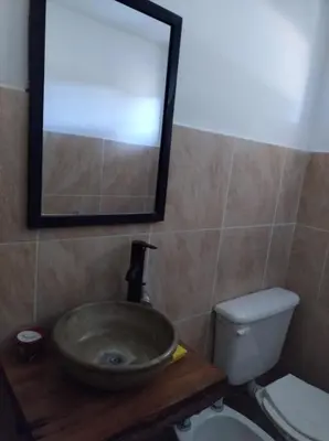 a bathroom with a sink and a toilet and a mirror at Cabañas MANKU in San Lorenzo
