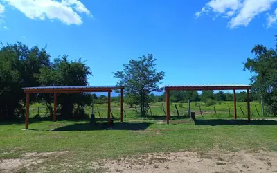 an empty park with two wooden structures in a field at Cabañas MANKU in San Lorenzo