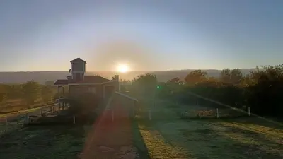 a building with a tower with the sun in the background at Cabañas MANKU in San Lorenzo