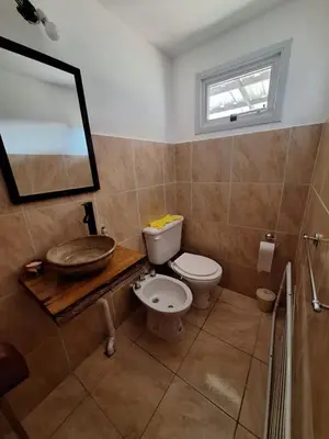 a bathroom with a toilet and a sink and a mirror at Cabañas MANKU in San Lorenzo