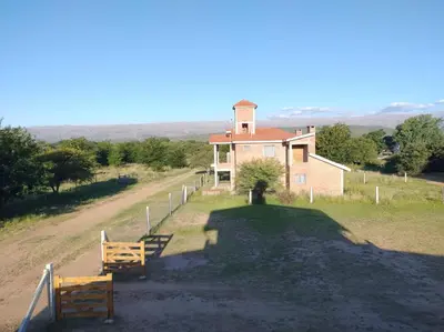 a house on a hill with two benches in front of it at Cabañas MANKU in San Lorenzo