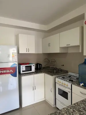 a kitchen with white cabinets and a stove and a refrigerator at Apart San Jose a 200mts de la peatonal in Villa Carlos Paz