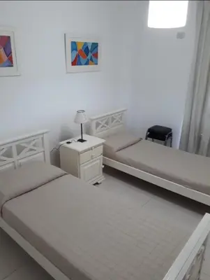 a bedroom with two beds and a dresser with a lamp at Dos Nogales 26 in Villa Carlos Paz