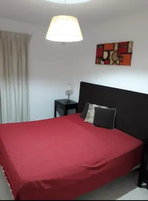a bedroom with a red bed with a red blanket at Dos Nogales 26 in Villa Carlos Paz