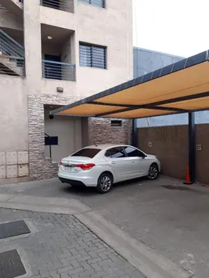 a white car parked in a parking lot next to a building at Dos Nogales 26 in Villa Carlos Paz