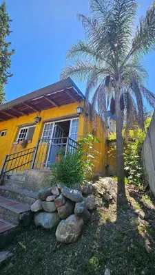a yellow house with a palm tree in front of it at Balcón de las sierras in Villa Carlos Paz
