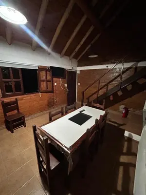 a dining room with a table and chairs and stairs at Cabaña petiza in Mina Clavero