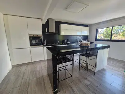 a kitchen with a black counter and white cabinets at Hermosa Casa en Villa del Lago Carlos Paz Vista al lago, zona exclusiva y residencial in Cordoba