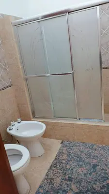 a bathroom with a toilet and a glass shower at Departamentos Elisabeth in Tanti