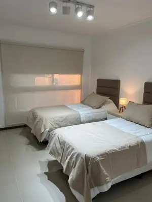 two beds in a white room with a window at Departamento centrico en carlos paz in Villa Carlos Paz