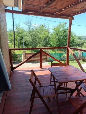 a wooden porch with a wooden table and a bench at Aves Del Monte in Santa Rosa de Calamuchita