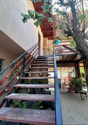 a set of stairs leading to a building with a tree at Departamento de 2 a 5 personas in Villa Carlos Paz