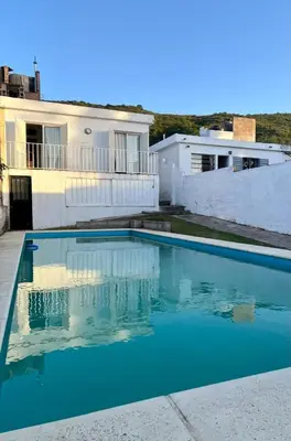 a blue swimming pool in front of a house at Casa con Pileta, solo para familias in Villa Carlos Paz