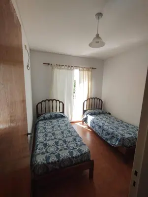 two beds in a room with a window at Casa con Pileta, solo para familias in Villa Carlos Paz