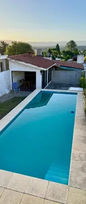 a blue swimming pool in front of a house at Casa con Pileta, solo para familias in Villa Carlos Paz