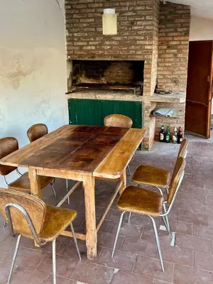 a wooden table and chairs in a room with a fireplace at Casa con Pileta, solo para familias in Villa Carlos Paz