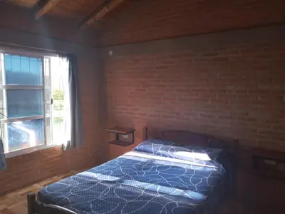 a bedroom with a bed and a brick wall at Cabaña las chinitas in San Lorenzo