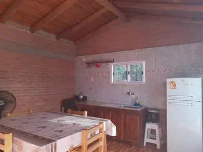 a kitchen with a table and a white refrigerator at Cabaña las chinitas in San Lorenzo