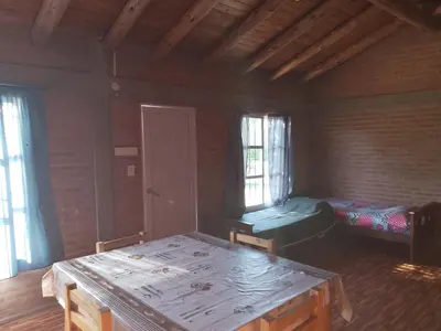 a room with a table and a bed and windows at Cabaña las chinitas in San Lorenzo