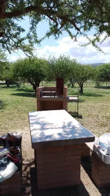 a picnic table sitting under a tree in a field at Cabaña las chinitas in San Lorenzo