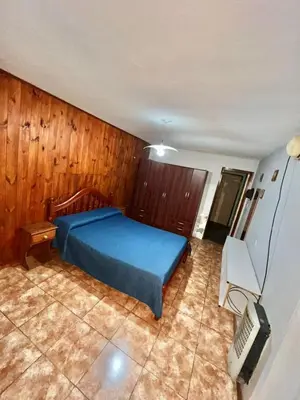 a bedroom with a blue bed and wooden walls at La roca in Villa Carlos Paz