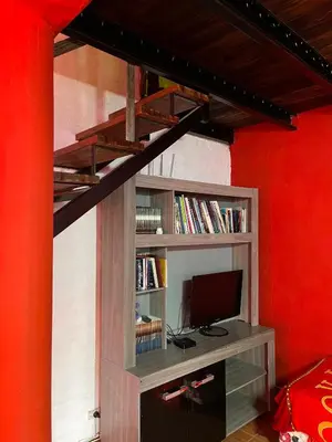 a room with a book shelf with a computer monitor at La Morada in Mina Clavero