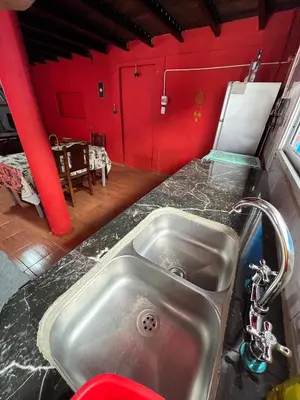 a kitchen with a sink and a red wall at La Morada in Mina Clavero