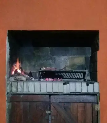 a brick fireplace with a fire in it at Arcadia in Merlo