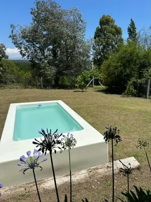 a swimming pool in a yard with purple flowers at Casita de los Reartes in Los Reartes