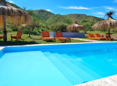 a swimming pool with chairs and umbrellas at Complejo MAS vista in San Antonio de Arredondo
