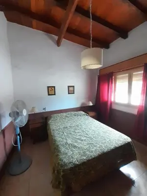 a bedroom with a bed with a fan and a window at Don Nene in Villa Cura Brochero