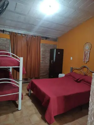 a bedroom with a bed with a red bedspread at Tia Clau 1 in Villa Cura Brochero